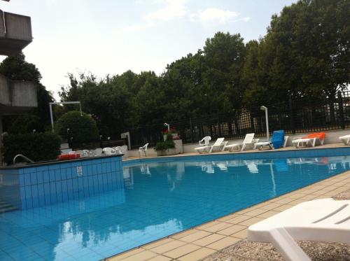 a large swimming pool with white chairs at Park Hotel in Castrocaro Terme