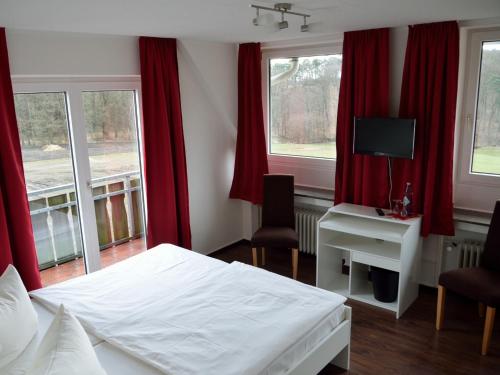 Schlafzimmer mit einem weißen Bett und roten Vorhängen in der Unterkunft Forsthaus Schöntal in Aachen