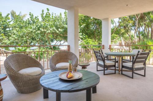 eine Terrasse mit einem Tisch und Stühlen sowie einem Tisch und Stühlen in der Unterkunft Itz'ana Resort & Residences in Placencia Village