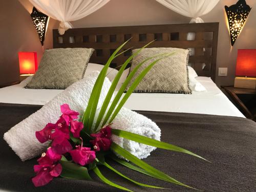 - une chambre avec 2 lits avec des fleurs roses sur le lit dans l'établissement Domaine de l'Anse des Rochers, à Saint-François