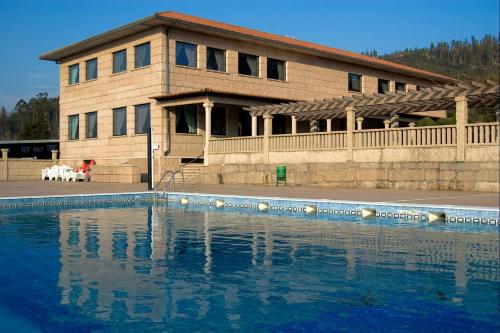 a house with a swimming pool in front of a building at Hotel Scala in Padrón