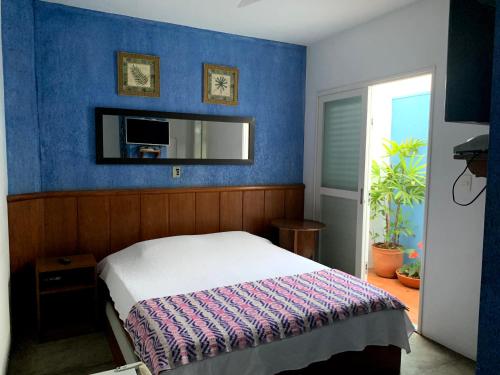 1 dormitorio con cama y pared azul en Pousada Manga Rosa en São João Batista do Glória