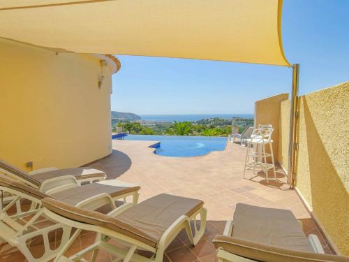 モライラにあるGreat villa in Moraira with infinity poolのパティオ(椅子付)、プールの景色を望めます。