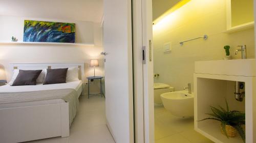 a white bedroom with a bed and a bathroom at Stesicoro Exclusive House in Catania