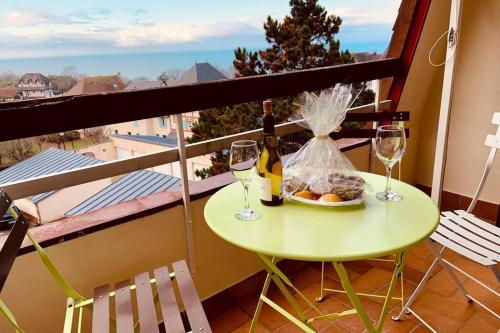 - une table avec des verres à vin et une assiette de nourriture sur le balcon dans l'établissement Trouville-Apt rénové-Balcon magnifique vue mer, à Trouville-sur-Mer