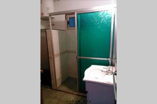 a bathroom with a green shower and a sink at Casa ideal para descansar Piriápolis in Piriápolis