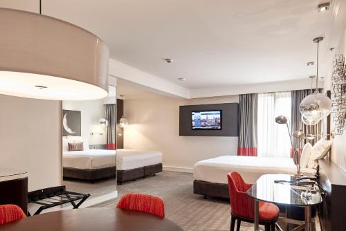 a hotel room with a tv, couch, coffee table, and chairs at Pullman Melbourne Albert Park in Melbourne