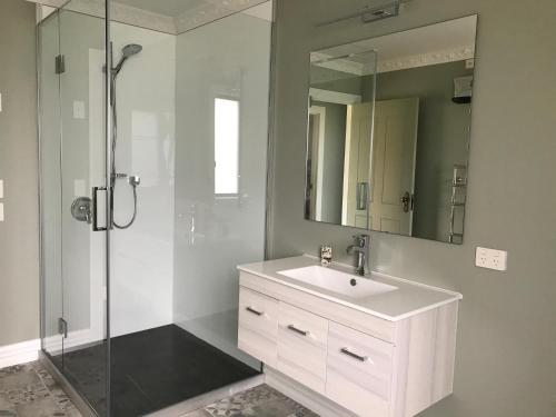 a white bathroom with a sink and a shower at Kepler Oaks Chalet in Te Anau