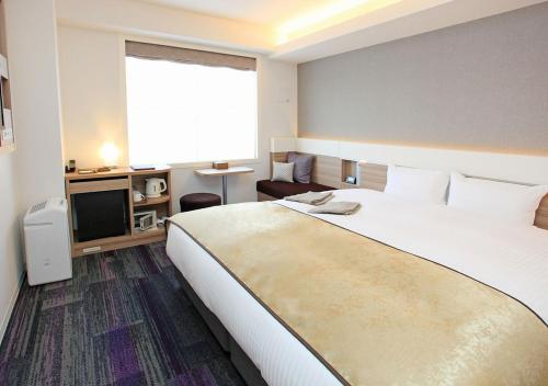 京都市にあるアーバンホテル京都五条プレミアムの大型ベッドとテレビが備わるホテルルームです。
