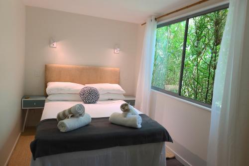 een slaapkamer met 2 handdoeken op een bed met een raam bij Orchard Cottage - modern Australian Sunshine Coast holiday cottage on organic farm nr beach in Valdora