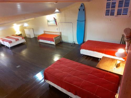 Habitación con 3 camas y tabla de surf en la pared en Apartamento Condominio Belle Vie, en Búzios