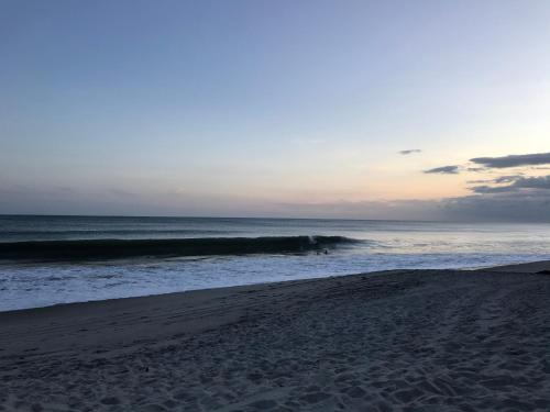 a beach with a group of surfers in the ocean at Playa Caracol Beachfront Residence Club in Chame