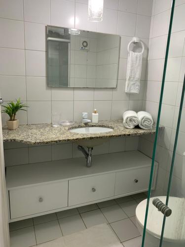 un bagno con lavandino e specchio di Apartamento Porto Praia do Forte a Praia do Forte