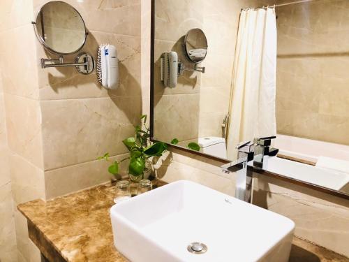 een badkamer met een witte wastafel en een spiegel bij Muong Thanh Quy Nhon Hotel in Quy Nhon