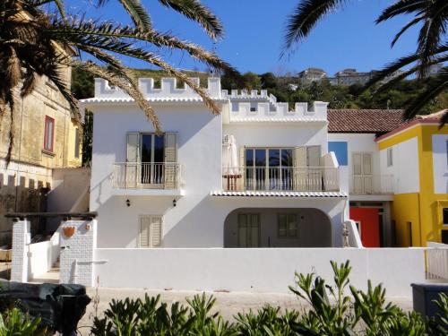 a white house with balconies and palm trees at Villino Erminia - Seaside Art b&b in Pizzo