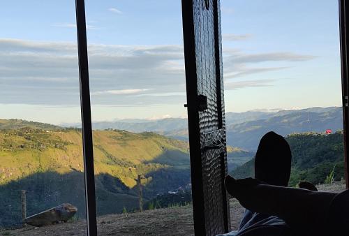 a person is looking out of a window at a mountain at Hotel Kasama in San Agustín