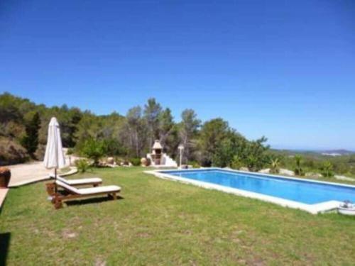 a yard with a pool and a umbrella and chairs at Can Ramón in Sant Josep de sa Talaia
