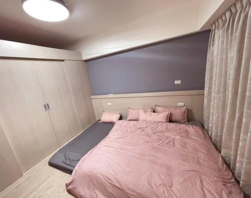 a bedroom with a large bed with pink sheets and pillows at 樂室Room in Nanwan