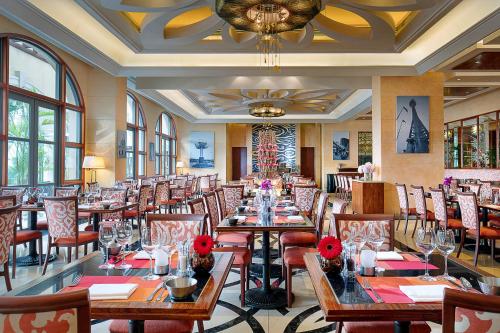 a restaurant with tables and chairs with red flowers on them at Sofitel Macau At Ponte 16 in Macau