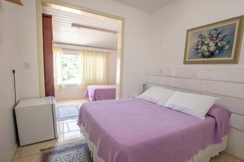 a bedroom with a purple bed and a window at Hotel Pousada Casa Tasca in Bento Gonçalves
