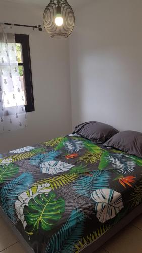 ein Bett mit farbenfroher Bettdecke in einem Schlafzimmer in der Unterkunft Villa Créole Alamanda in Petite Île