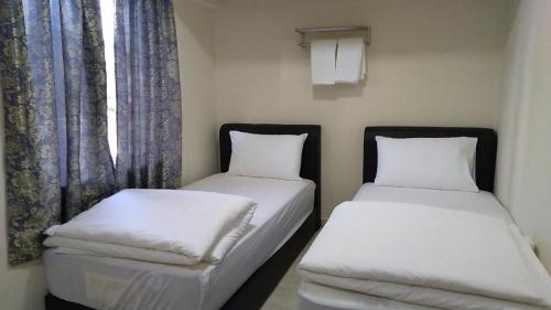 two twin beds in a room with a window at Axlite Hotel in Taiping