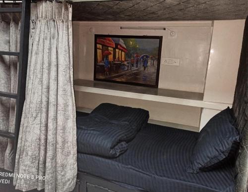 Cama en habitación con cortina y TV en Dormitory, en Udaipur
