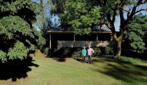two people standing in a yard in front of a house at Peaceful cabin in a rural setting 2km from CBD in Tamworth