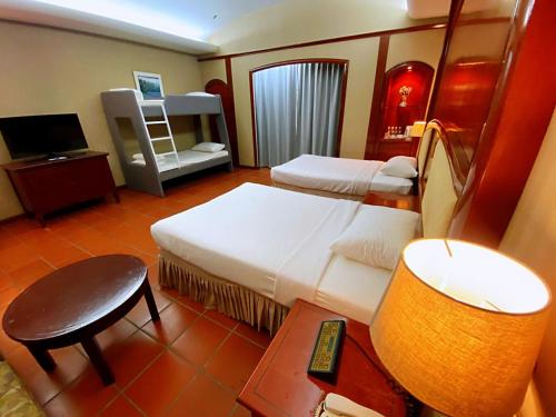 ein Schlafzimmer mit zwei Betten, einem Tisch und einer Lampe in der Unterkunft Ponderosa Golf & Country Resort in Johor Bahru