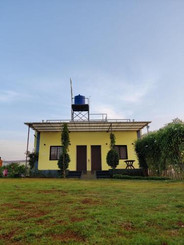 a yellow house with a water tank on the roof at Tripvana Patio Home in Nashik