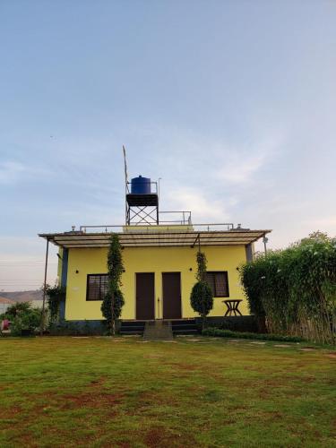 a yellow house with a tower on top of it at Tripvana Patio Home in Nashik