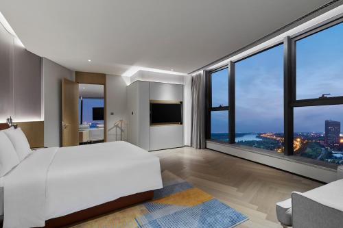 a bedroom with a white bed and large windows at EVEN Hotel Nanjing Yangtze River by IHG in Nanjing
