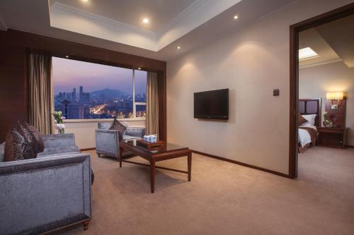a living room with a couch and a bed and a television at Hotel Nikko Wuxi in Wuxi