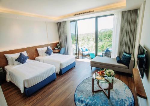 um quarto de hotel com duas camas e um sofá em FLC Grand Hotel Quy Nhon em Quy Nhon