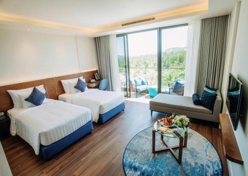 a hotel room with two beds and a couch at FLC Grand Hotel Quy Nhon in Quy Nhon