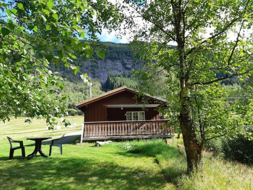 a cabin with a picnic table and a bench in the grass at Eidsdal Camping og Feriehus in Eidsdal