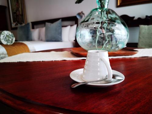 a glass vase on a table with a cup and spoon at Kleine Constantia Boutique Guest House in Roodepoort