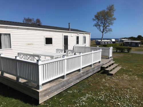 a large white house with a porch and a deck at Tobisviks Camping in Simrishamn