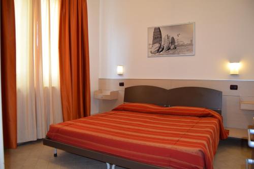 a bedroom with a bed with an orange comforter at Oasi del Mare in Tirrenia