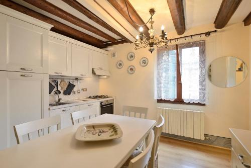 a kitchen with white cabinets and a table with chairs at Appartamento vista canale - Sant'Antonin in Venice