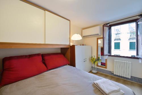 a bedroom with a bed with red pillows and a window at Appartamento vista canale - Sant'Antonin in Venice