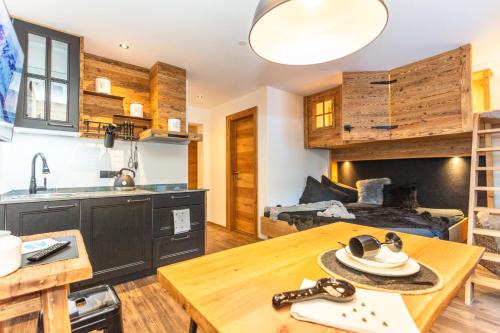 a kitchen and living room with a wooden table at Hotel Sonnberg in Saalbach Hinterglemm