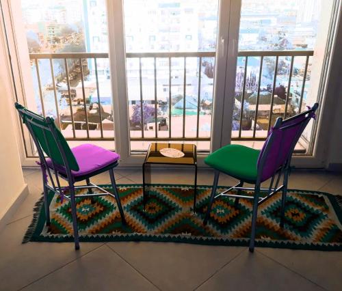 twee stoelen en een tafel voor een raam bij Isabel's B&B in Tirana