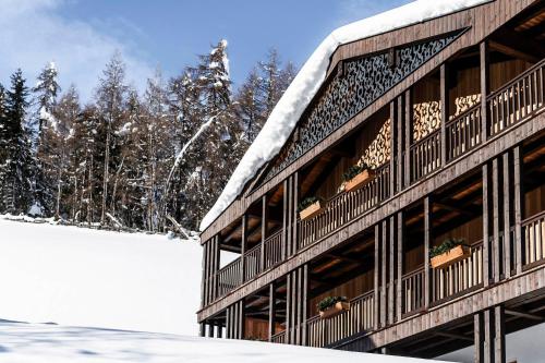a building covered in snow with trees in the background at La Majun Fornellahof in Antermoia