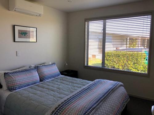 1 dormitorio con cama y ventana grande en Nikau’s on Palmer, en Foxton Beach