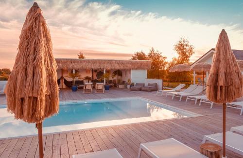 a villa with a swimming pool and umbrellas at Pastelowe Domki Wicie in Wicie