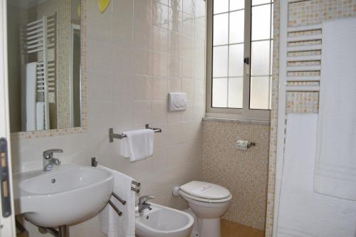 ein weißes Bad mit einem Waschbecken und einem WC in der Unterkunft Oasi del Mare in Tirrenia