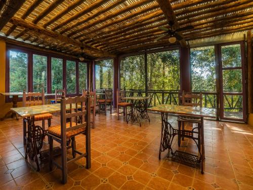 een eetkamer met tafels, stoelen en ramen bij Cabañas Tres Joyas in San Miguel Regla