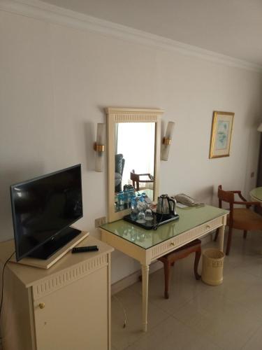 a living room with a table with a television and a mirror at Cairo Pyramids Hotel in Cairo