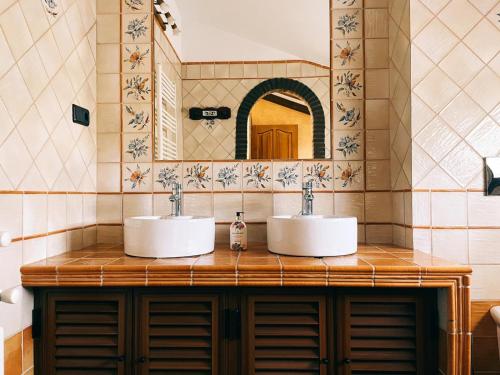 La salle de bains est pourvue de 2 lavabos et d'un miroir. dans l'établissement El recreo de Martalia, à Ronda